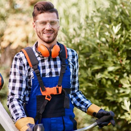 Élagueur en tenue de protection, tronçonneuse en main